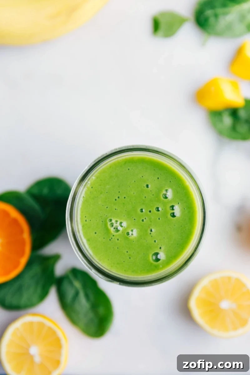 A delightful glass of healthy Green Smoothie, perfectly blended and ready for a refreshing sip. Healthy green smoothie in a glass, vibrant and ready to enjoy, surrounded by fresh citrus and spinach leaves.