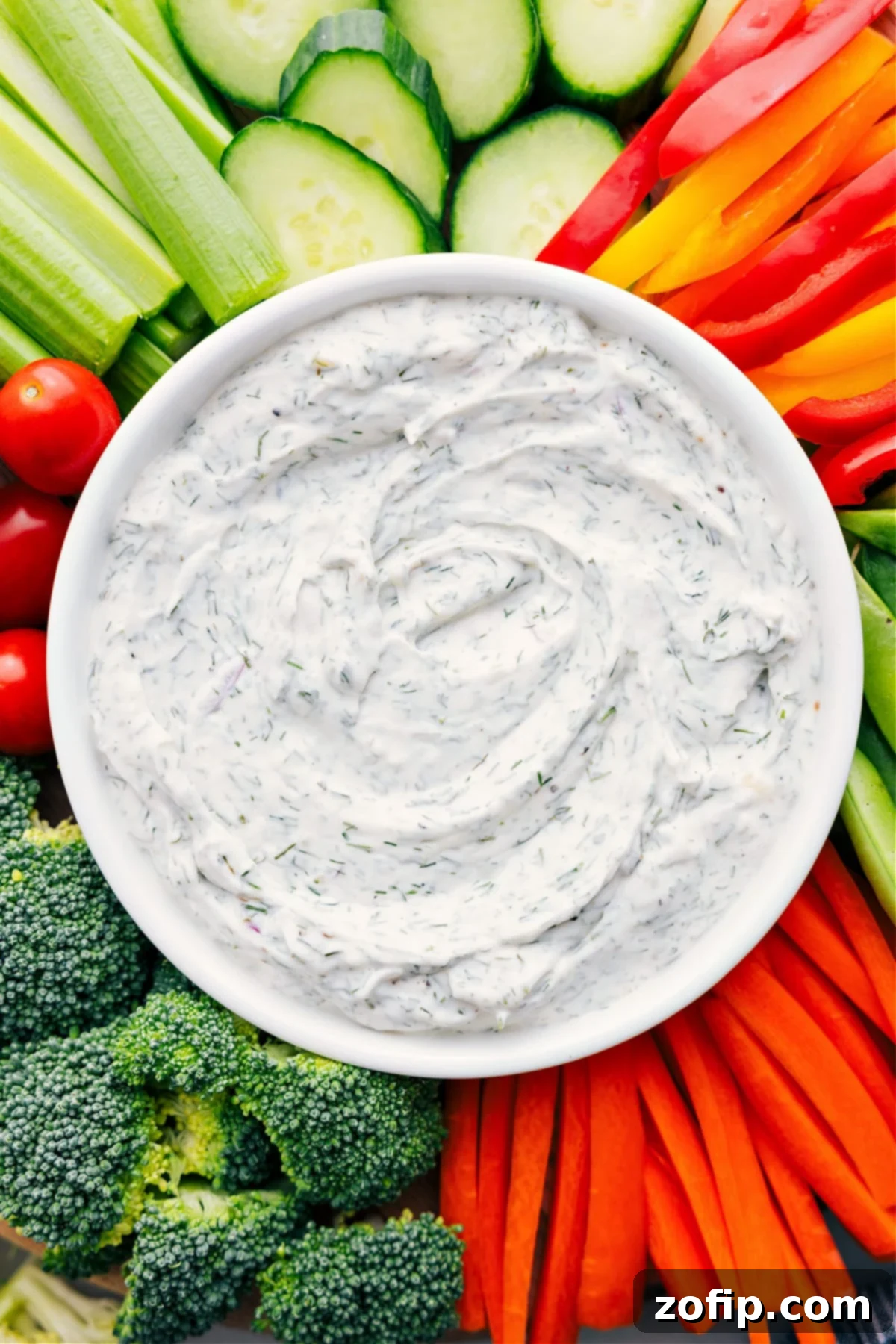Creamy Veggie Dip in a rustic bowl, generously surrounded by an assortment of vibrant, fresh vegetables like carrot sticks, cucumber slices, bell pepper strips, and cherry tomatoes, all ready for dipping and enjoying.