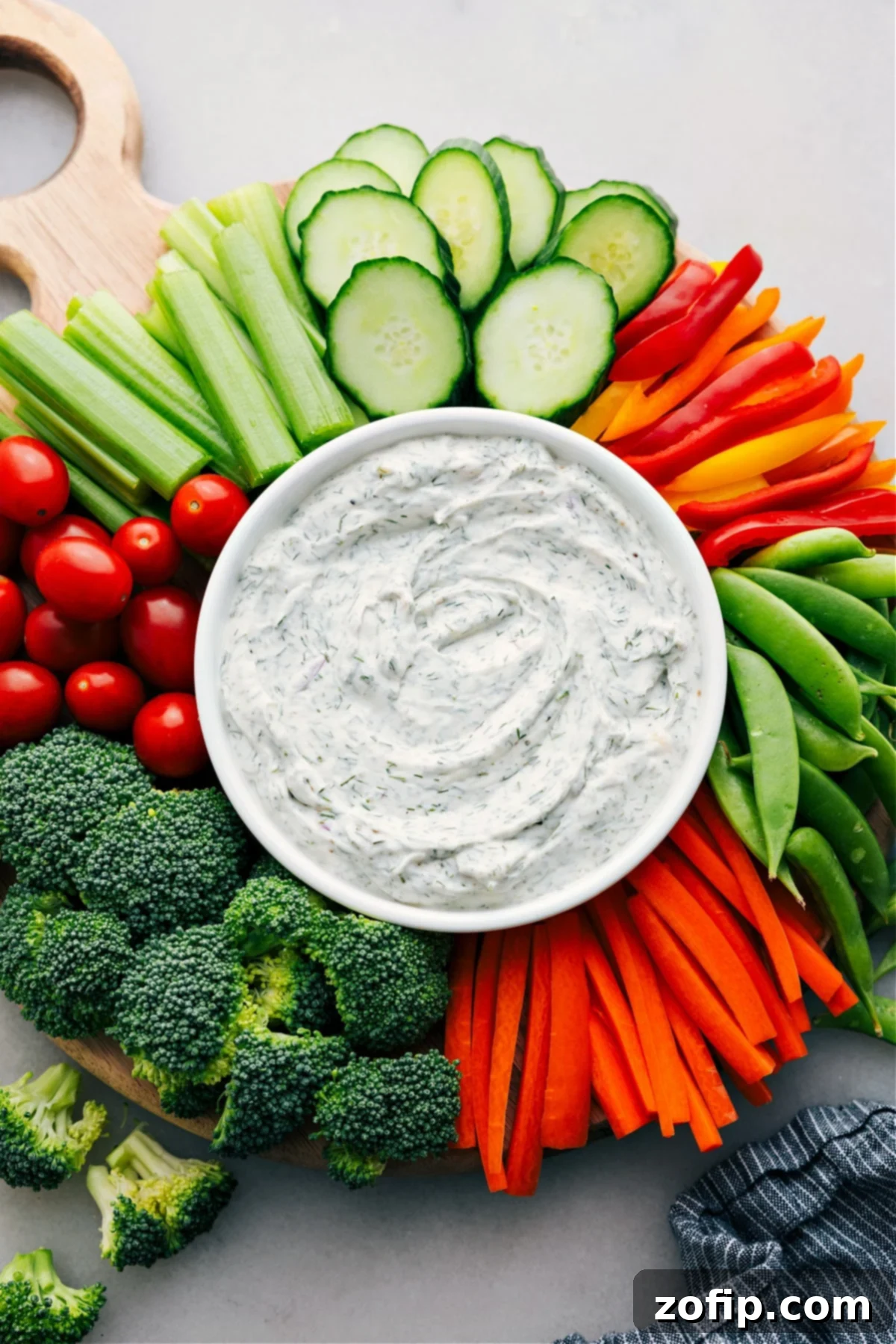 A beautifully arranged platter showcasing a bowl of creamy veggie dip nestled in the center, surrounded by a vibrant, diverse selection of fresh-cut vegetables, ideal for effortless entertaining or healthy everyday snacking.