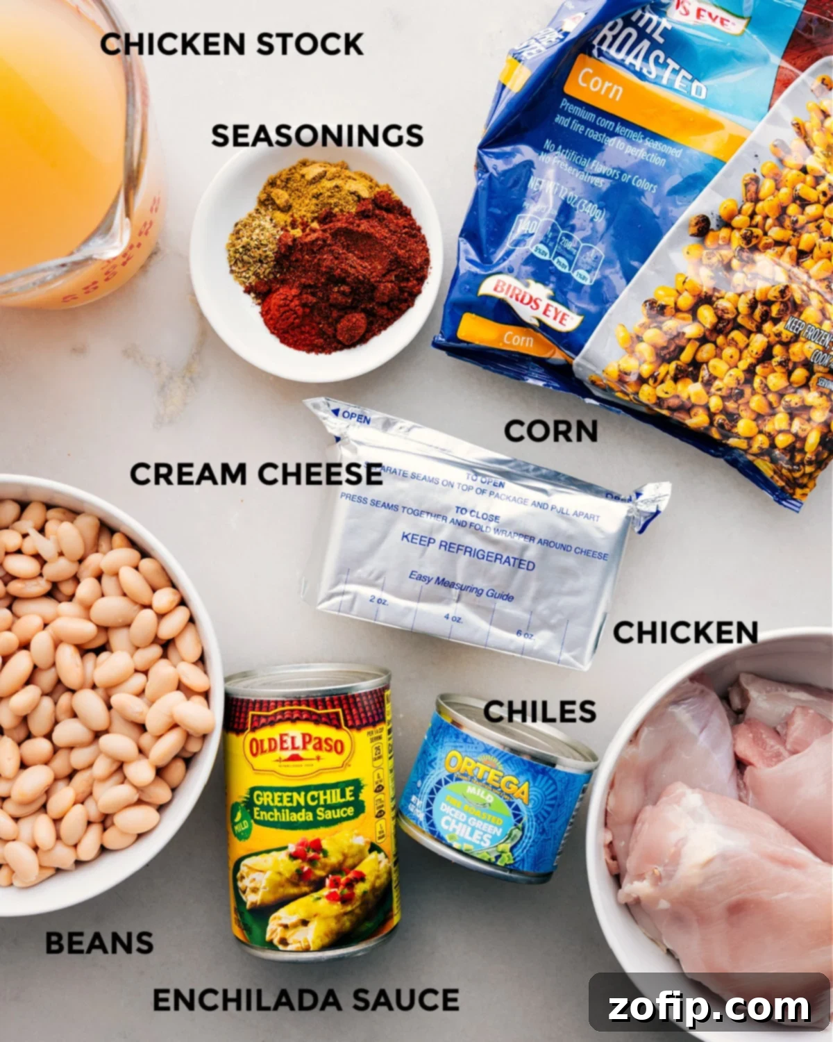 Ingredients In Crockpot White Chicken Chili Various ingredients for Crockpot White Chicken Chili, including chicken, green enchilada sauce, beans, corn, and spices.