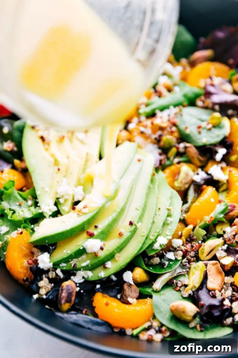 Close-up shot of the vibrant citrus dressing being poured generously over the assembled Citrus Quinoa Salad.