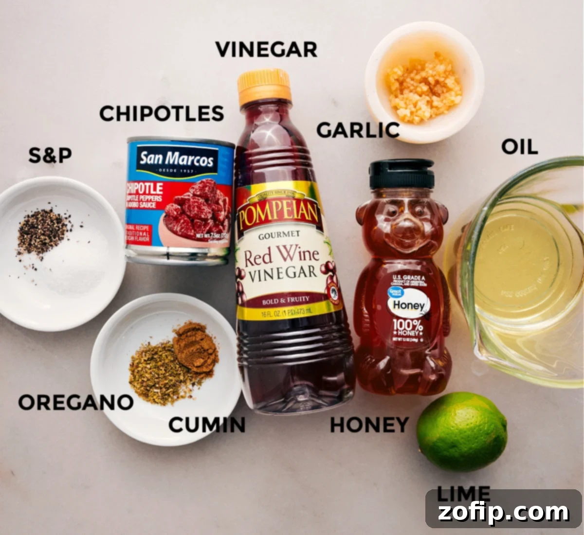 Ingredients for the chipotle-lime vinaigrette: red wine vinegar, fresh lime, olive oil, minced garlic, smoky chipotle peppers in adobo, and various seasonings, all ready to be blended for the quinoa corn salad.