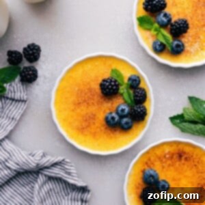 Golden crème brûlées with a crisp sugary top, garnished with fresh fruit, presented in white ramekins.