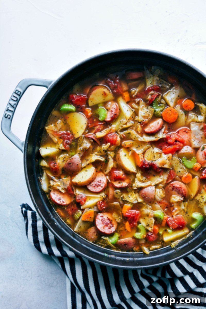 Hearty Sausage, Potato, and Cabbage Soup garnished with fresh herbs, ready to be served with crusty bread.