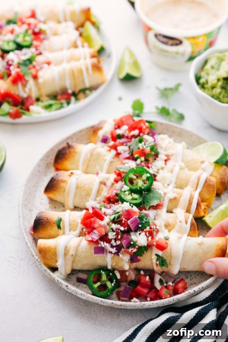 Close-up of golden brown baked chicken taquitos, showing the perfectly rolled tortillas and delicious filling peeking out.