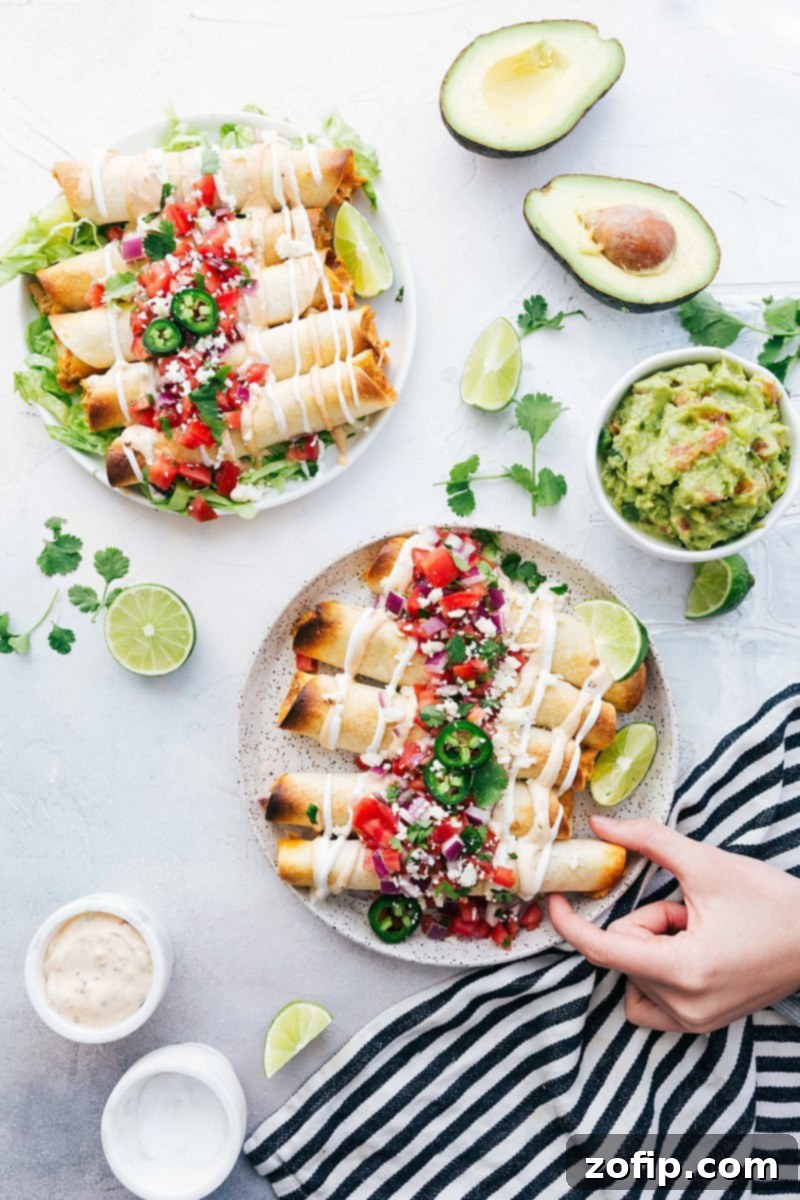 Baked chicken taquitos served on a plate with various toppings like guacamole, salsa, and cilantro.