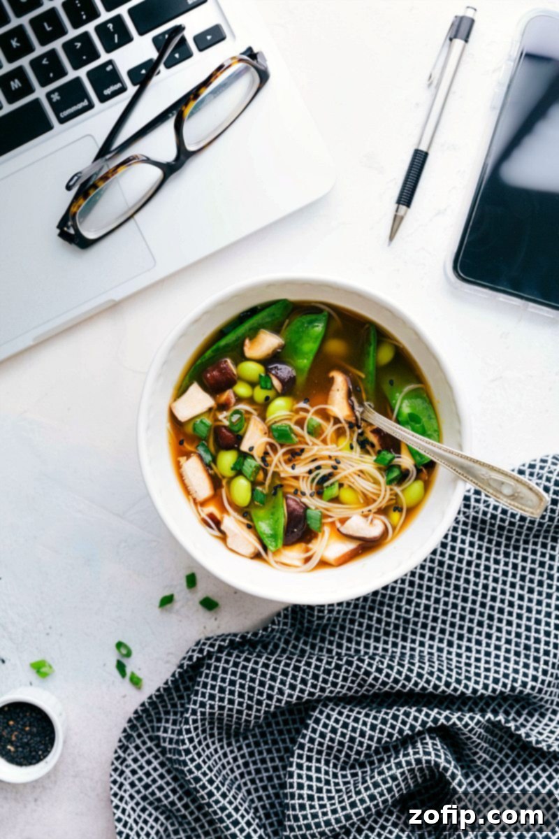 Vegetarian Edamame And Mushroom Recipe A vibrant Vegetarian Edamame and Mushroom noodle soup prepared in a bowl, garnished with green onions and sesame seeds, ready to be enjoyed.