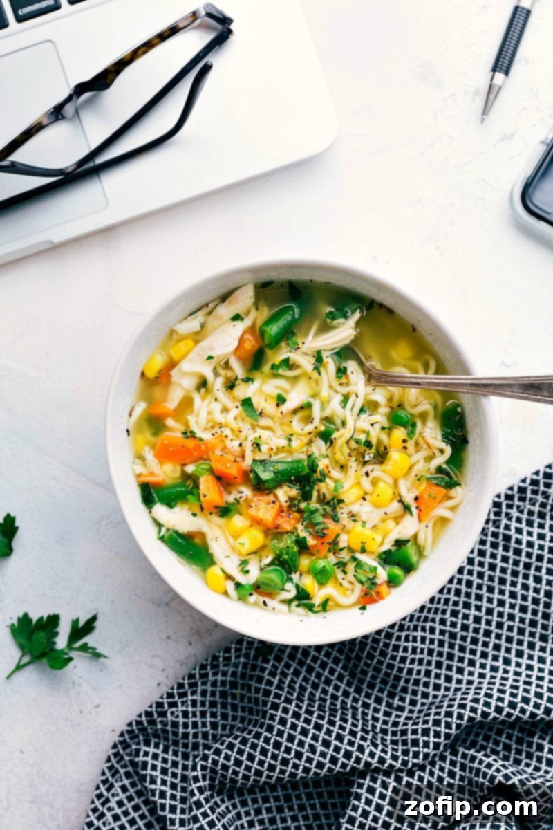 Flavorful And Simple Chicken And Veggie Soup Recipe A bowl of hot Chicken and Veggie Noodle Soup, garnished with fresh herbs, ready for a warm meal.