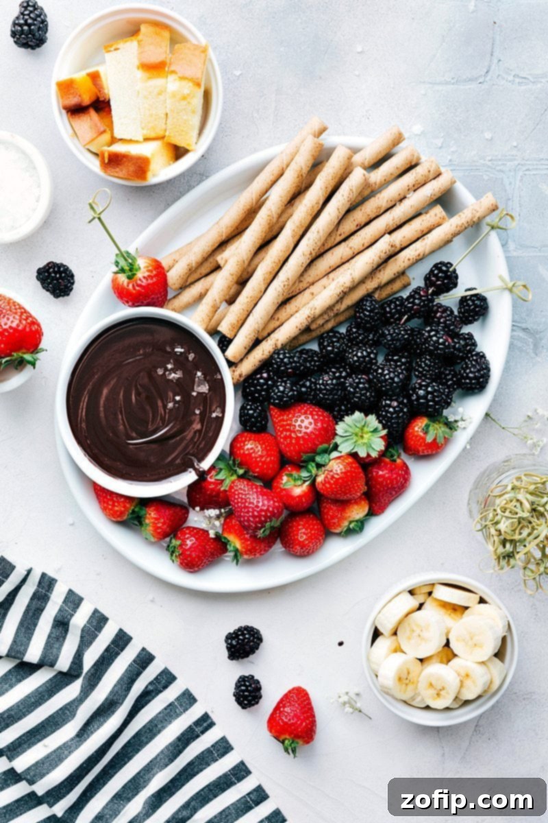 A bowl of the best easy chocolate fondue recipe surrounded by a variety of delicious treats perfect for dipping.