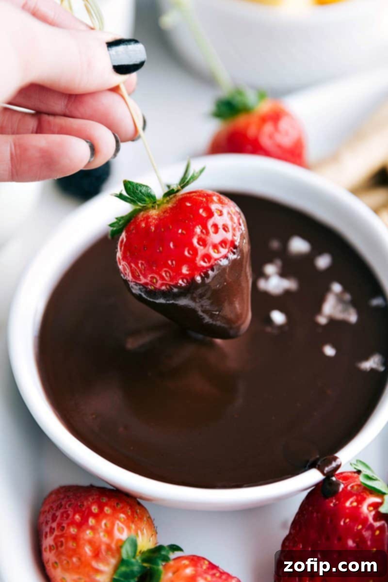 Author dipping a fresh strawberry into a rich bowl of homemade chocolate fondue.