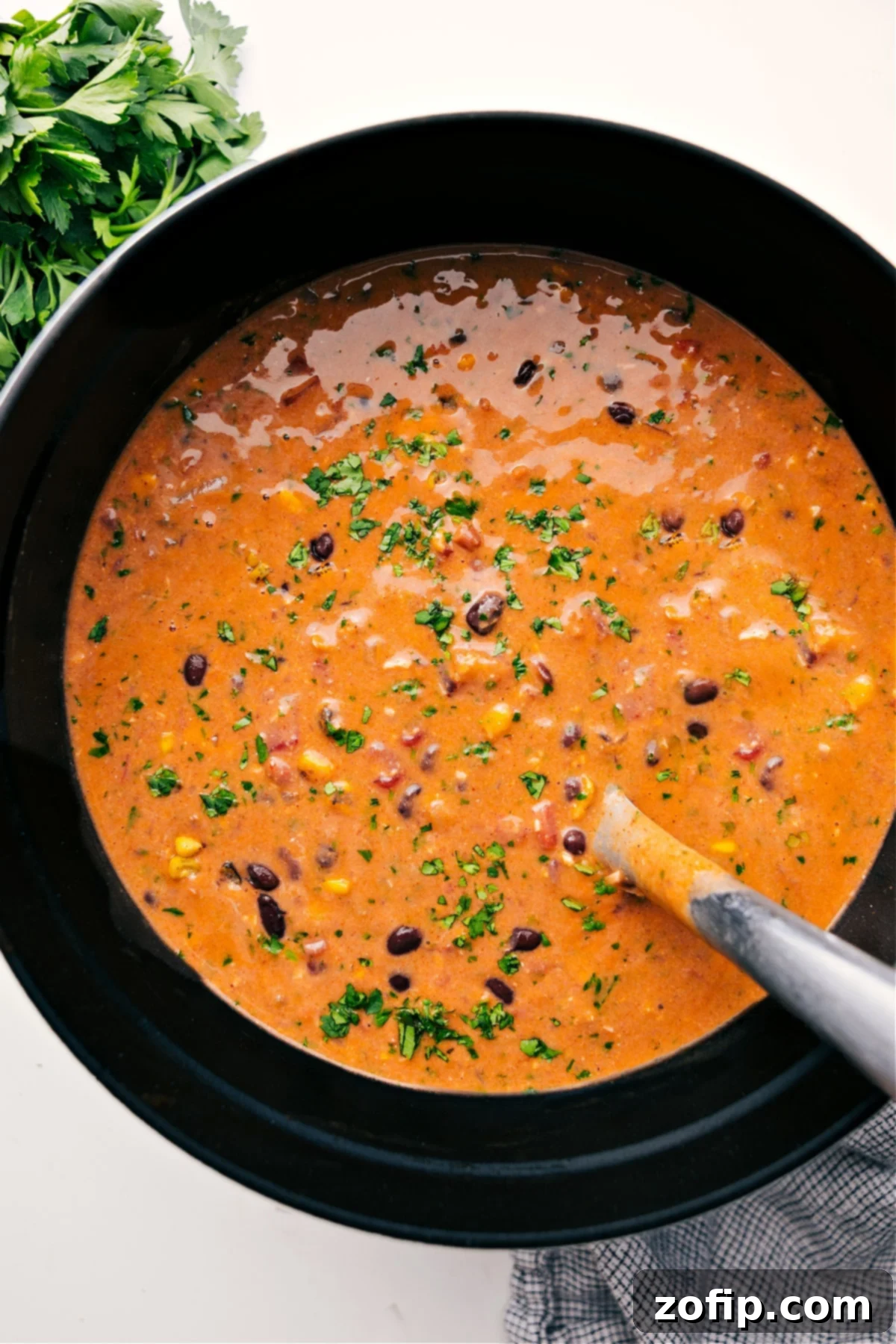 A large pot filled with steaming chicken tortilla soup, garnished with fresh cilantro and lime wedges, ready to be served.