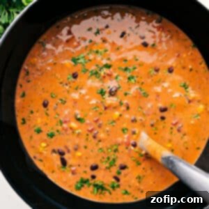 A close-up of a bowl of vibrant Chicken Tortilla Soup with toppings.