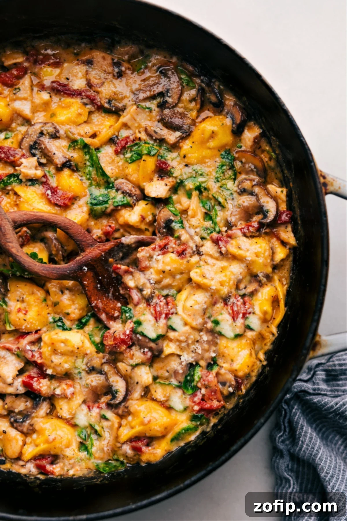 A close-up shot of Marry Me Chicken Tortellini, freshly baked and garnished with herbs, ready to be served from the pan.