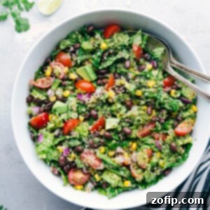 A bowl filled with a flavorful and healthy southwest quinoa salad, accompanied by two serving spoons on the side.