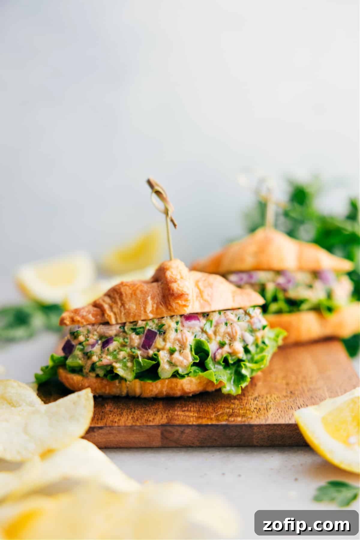 A perfectly prepared tuna salad served elegantly on a flaky croissant, ready to be enjoyed.