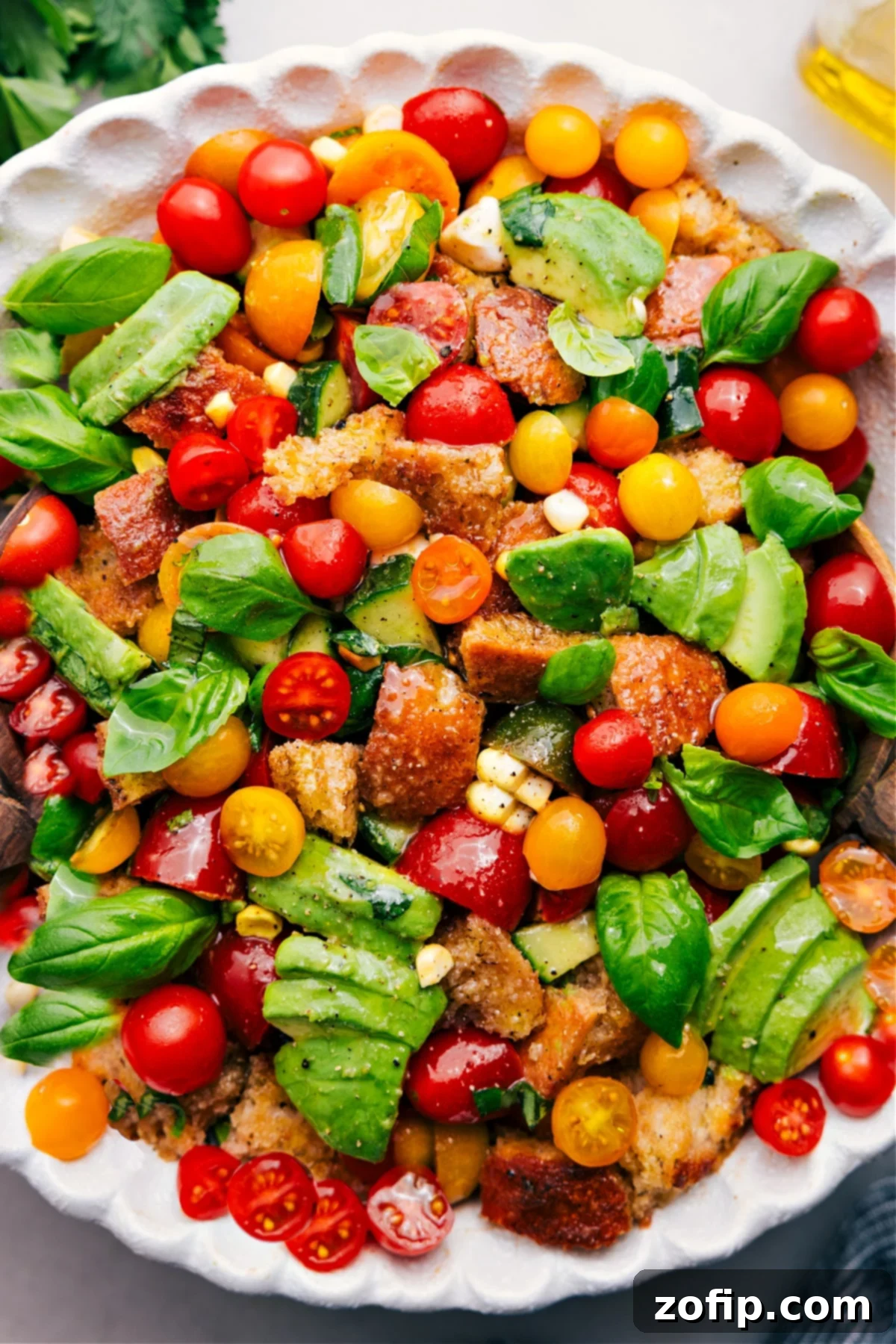 Panzanella salad with fresh tomatoes, avocado, basil, corn, and bread. A vibrant and colorful summer dish.