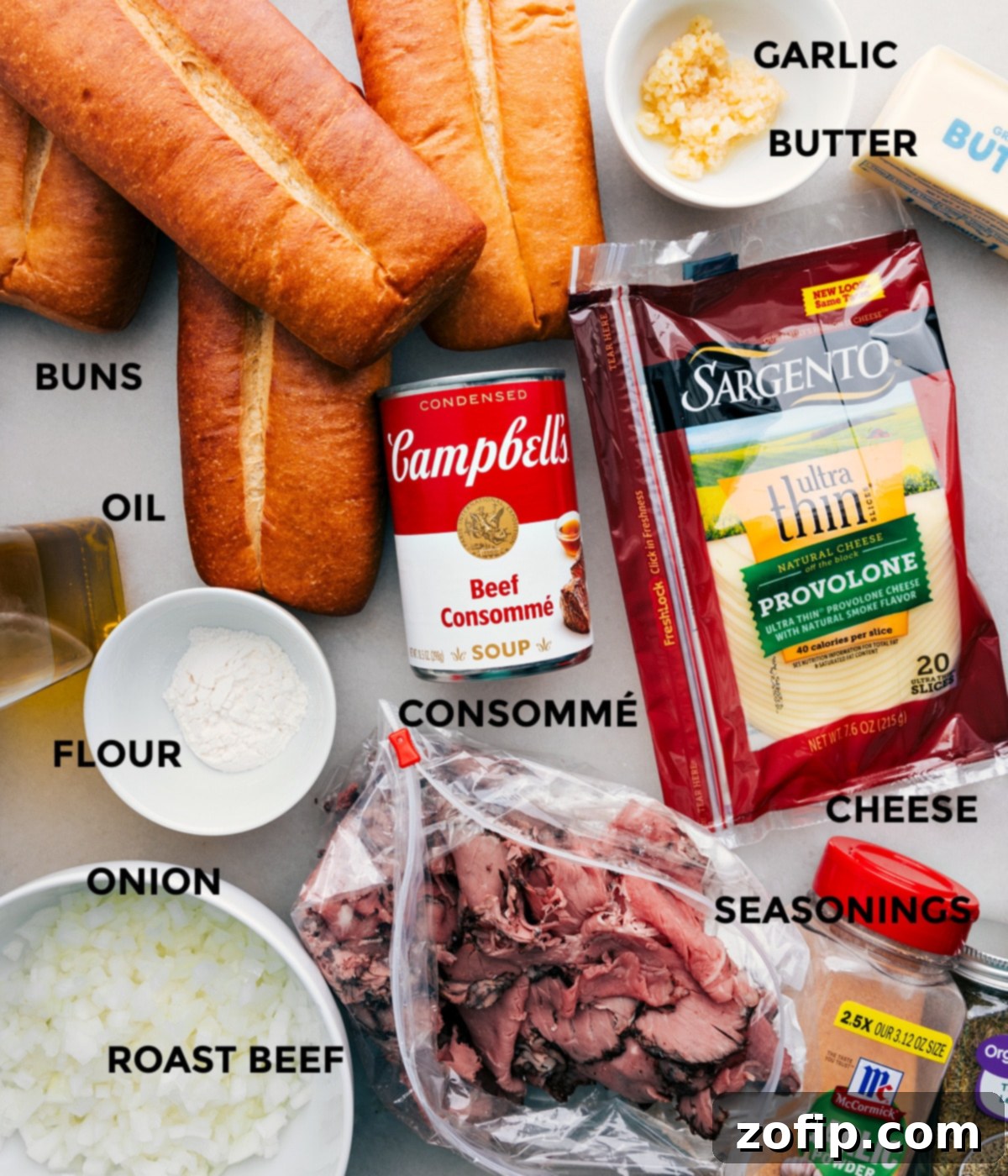 All the ingredients including buns, olive oil, flour, onions, roast beef, garlic, butter, cheese, seasonings, and beef consomme prepped out for easy assembly.