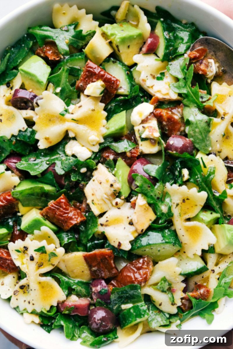 Vibrant Mediterranean Pasta Salad 7 A beautifully presented bowl of Mediterranean Pasta Salad on a rustic wooden surface, garnished with fresh herbs.