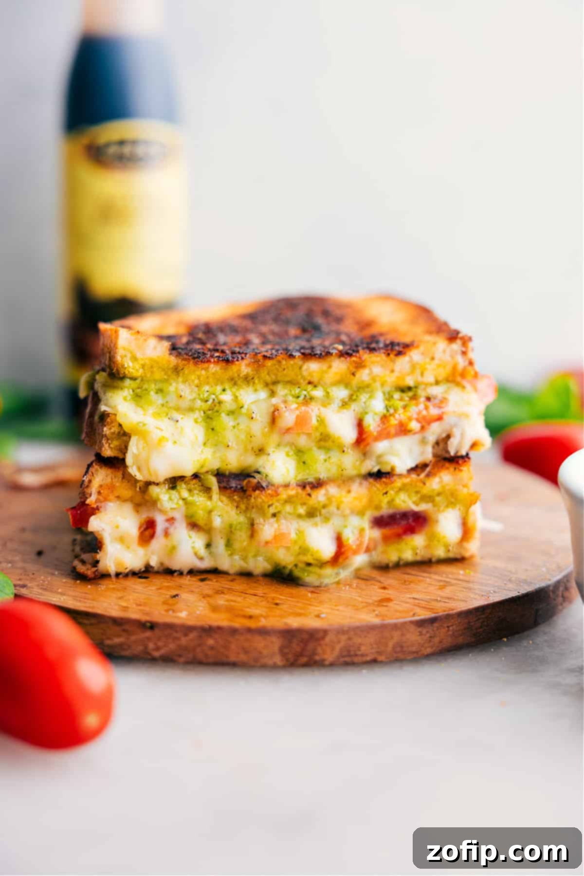 Caprese Grilled Cheese stacked on top of each other showing the cheesy center, with fresh basil and a drizzle of balsamic glaze.