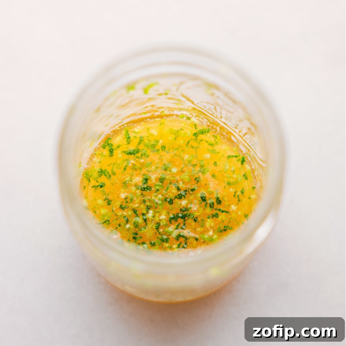 Zesty Tropical Fruit Bowl A Simple Indulgence 4 A small jar filled with the vibrant honey-lime dressing, garnished with a lime wedge and a drizzle of honey, ready to be added to the Tropical Fruit Salad.