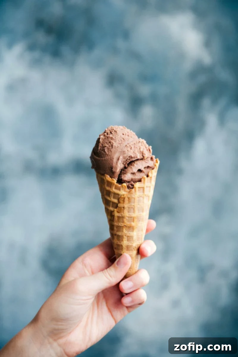 Homemade Chocolate Gelato in a Waffle Cone A waffle cone cone filled with rich and creamy chocolate gelato, showcasing its smooth texture and deep color.
