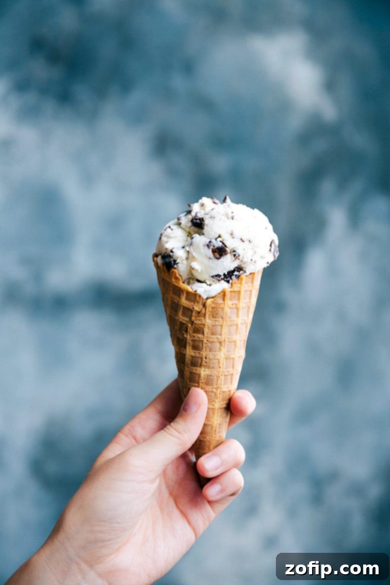 Classic Stracciatella Gelato in Waffle Cone Stracciatella gelato in a waffle cone being held, showcasing the delicate chocolate shards within the creamy vanilla base.