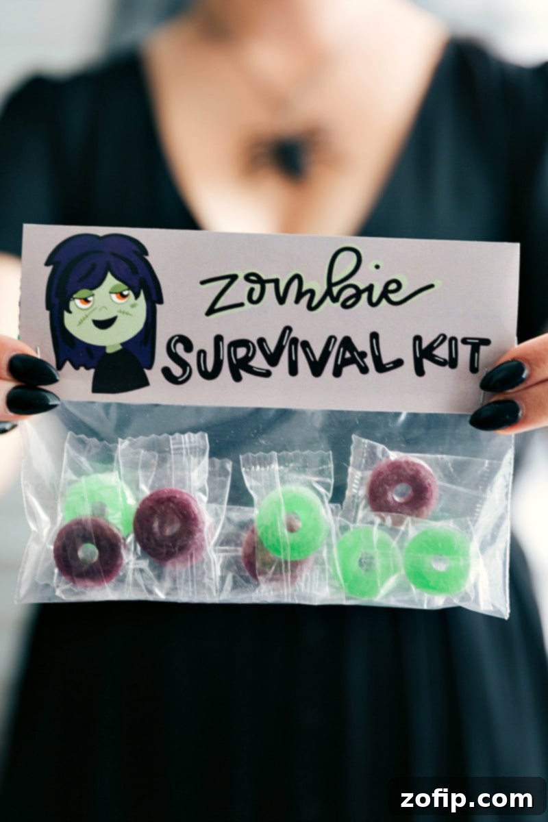 A quirky 'Zombie Survival Kit' Halloween treat bag featuring a gruesome green zombie hand on its topper, filled with colorful Lifesavers candies.