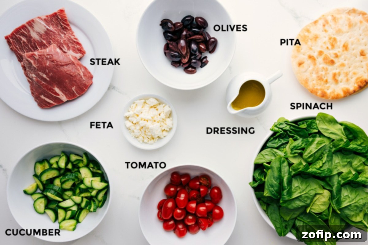 Ingredients In Grilled Steak Salad Recipe All fresh ingredients prepped and arranged for easy assembly of Grilled Steak Salad, including thinly sliced grilled steak, Kalamata olives, grilled pita wedges, fresh baby spinach, vibrant honey-lemon dressing, crumbled feta cheese, juicy cherry tomatoes, and crisp cucumber slices.