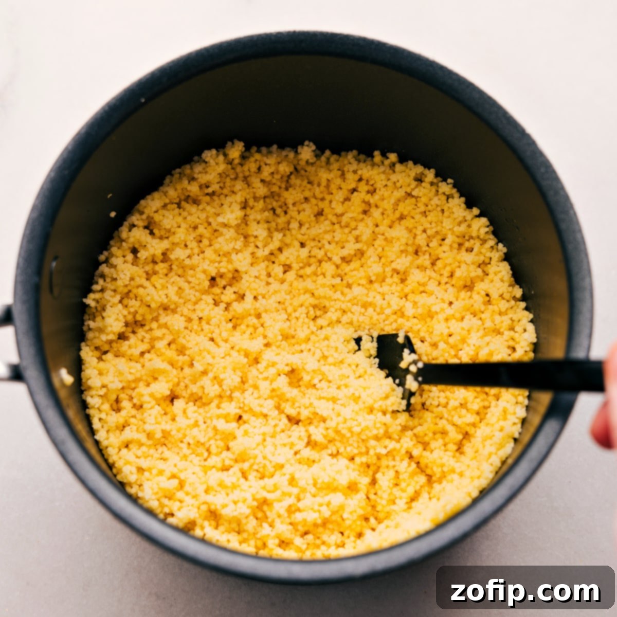 Fluffy couscous perfectly prepped and fluffed in the pot, ready to be added to the Mediterranean salad mixture.