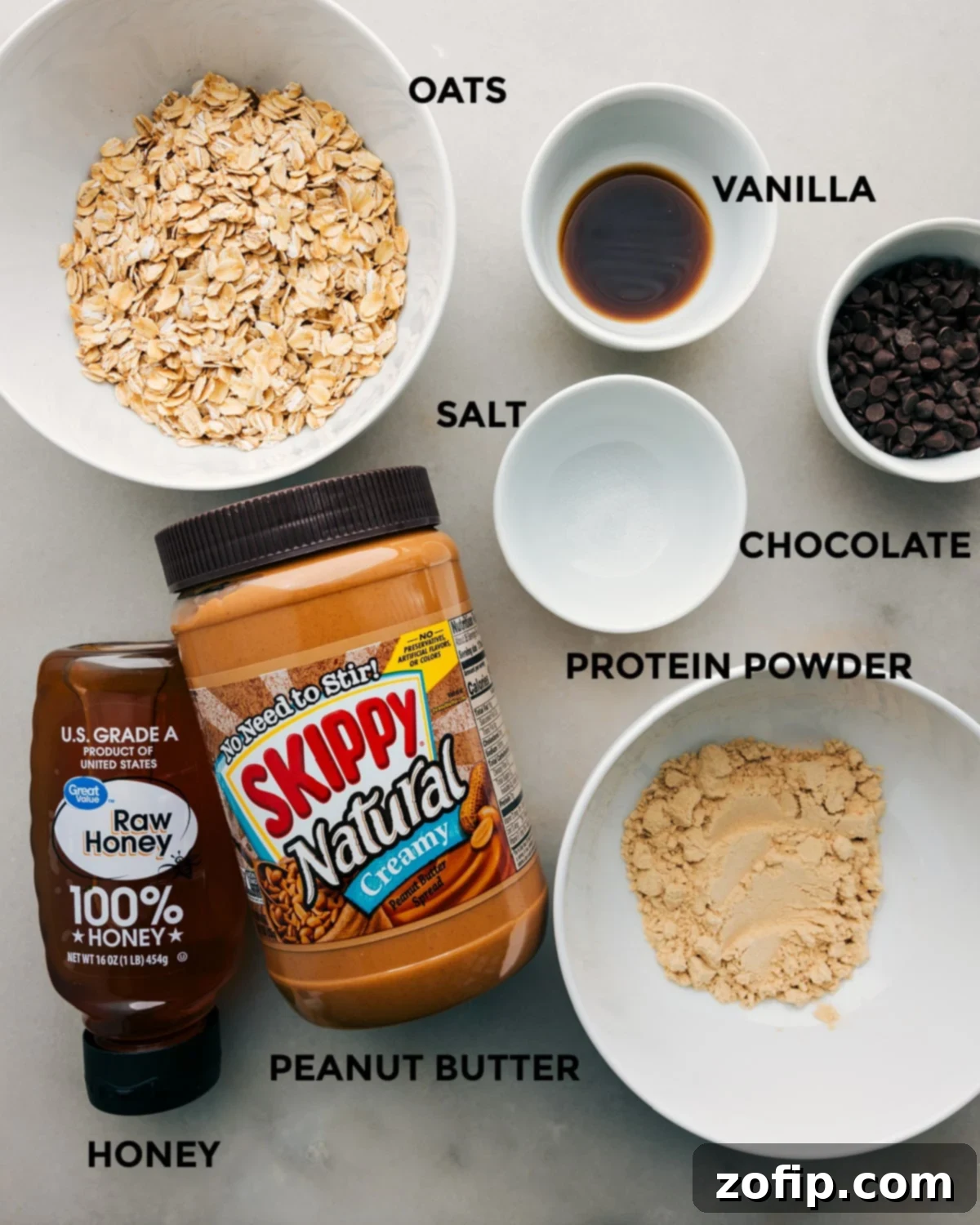 All the ingredients for homemade protein bars prepped out for easy assembly, including oats, peanut butter, honey, protein powder, and chocolate chips.