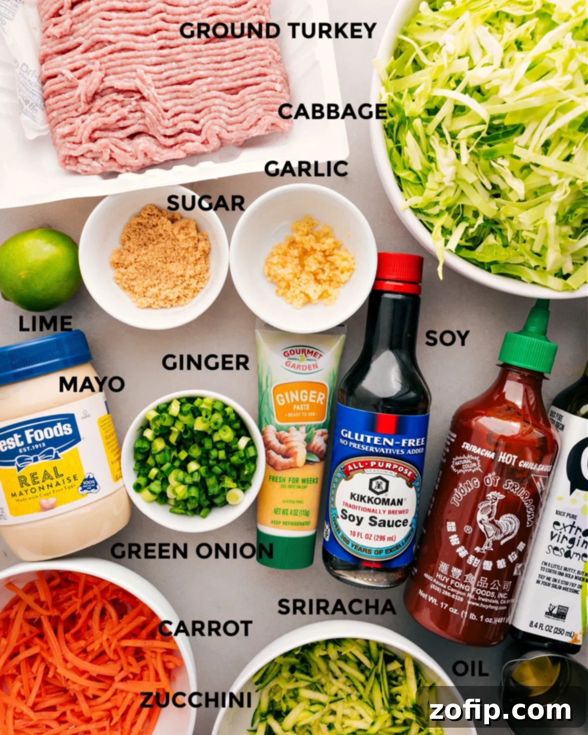 All the fresh ingredients for a delightful Ground Turkey Stir Fry, neatly prepped and arranged: lean ground turkey, thinly sliced cabbage, shredded carrots, zucchini, ginger paste, minced garlic, green onions, and the stir-fry sauce components including soy sauce, sesame oil, Sriracha, brown sugar, and cooking oil.