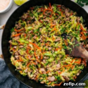 Delicious Ground Turkey Stir Fry in a white bowl, topped with sesame seeds and green onions, with chopsticks resting on the side.