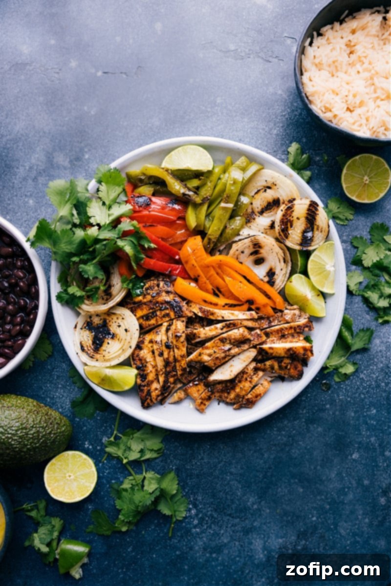 A vibrant platter of grilled chicken fajitas with colorful bell peppers, onions, and fresh lime wedges, ready to be served.