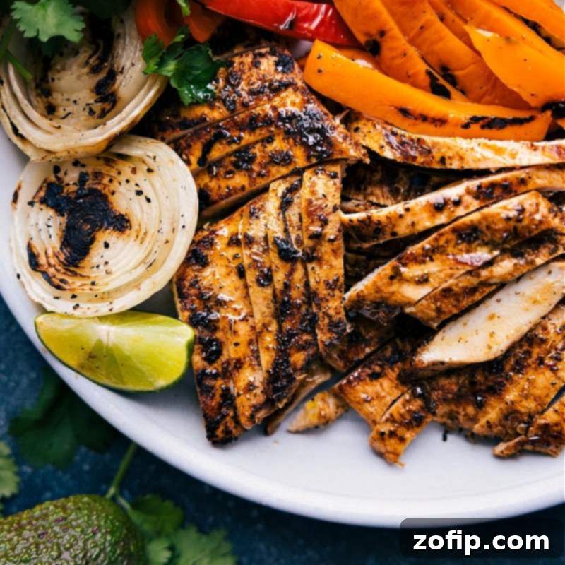 Close-up of perfectly grilled chicken and vibrant fajita vegetables (bell peppers and onions) on a grill, showing excellent charring.