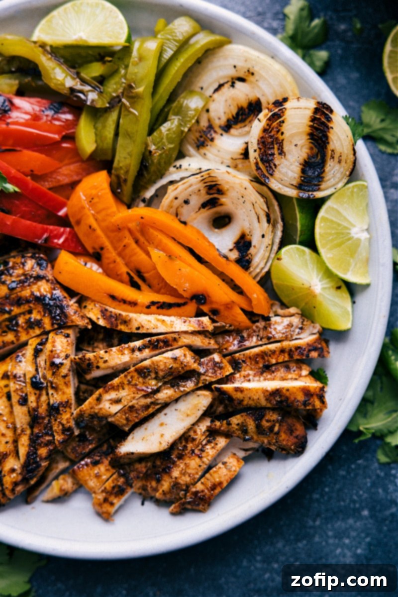 A beautifully arranged fajita platter with grilled chicken, colorful vegetables, fresh cilantro, lime wedges, and a bowl of cilantro lime rice.
