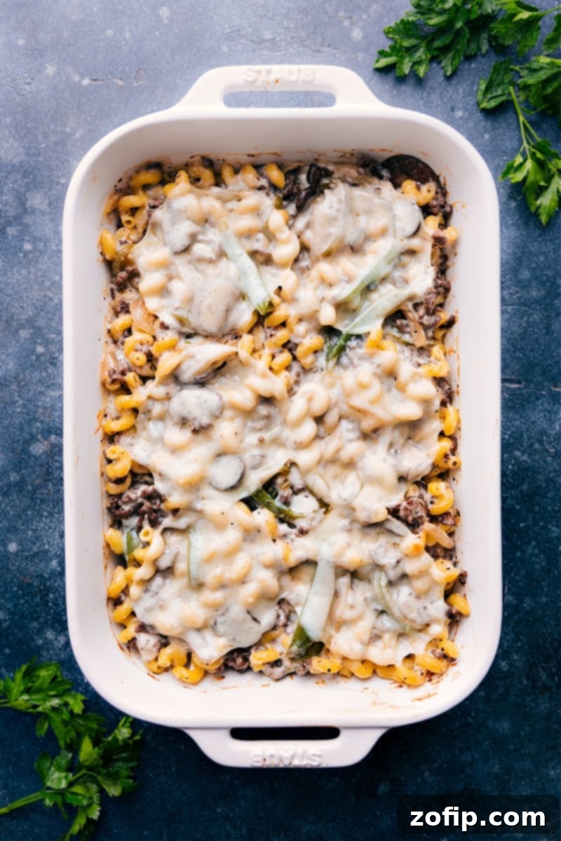 Overhead image of the complete Philly cheesesteak pasta bake in a casserole dish, garnished with fresh parsley.