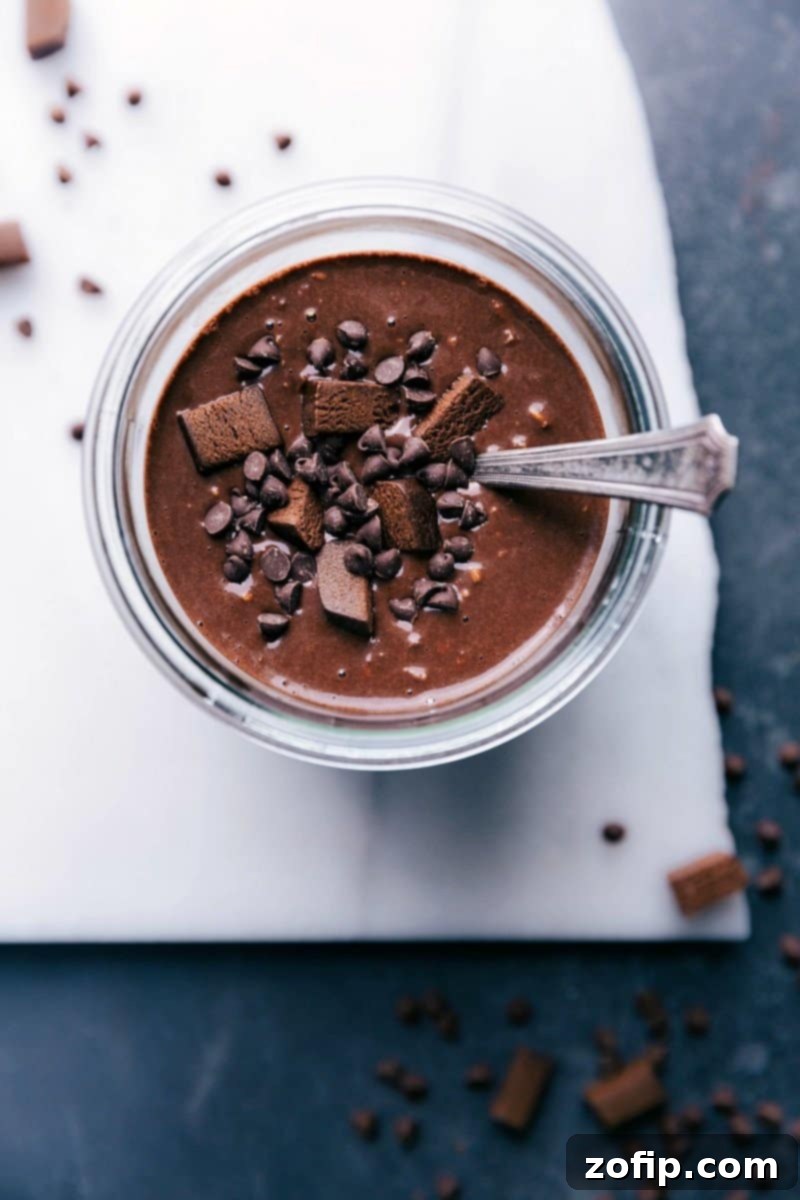 Brownie batter overnight oats, topped with chocolate chips and brownie bites for a sweet and delicious breakfast treat. A jar filled with creamy, dark chocolate oats sits adorned with rich toppings, promising a delightful morning.