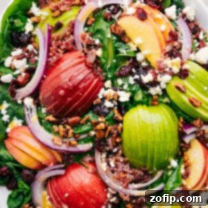 A fresh and vibrant spinach salad with apples, bacon, feta, cranberries, and pecans.