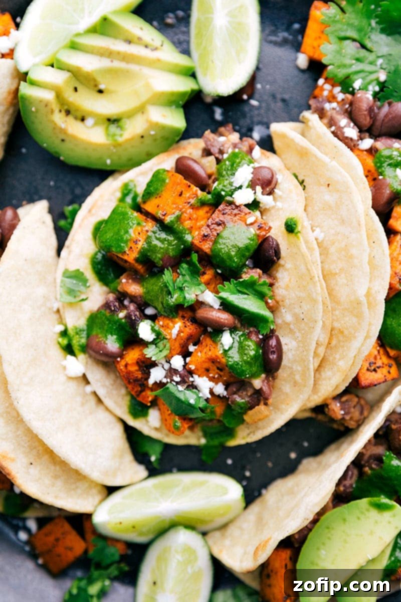 Roasted sweet potatoes and black bean tacos served with a delicious cilantro-lime sauce make the BEST easy Vegetarian Tacos! Beautifully assembled Vegetarian Tacos garnished with fresh cilantro, avocado, and a generous drizzle of homemade cilantro-lime dressing.
