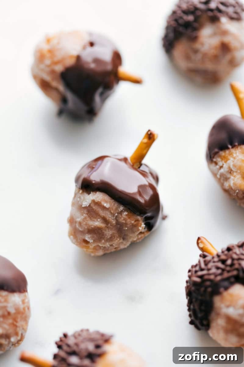 A festive platter of finished Acorn Donut Holes, beautifully arranged and ready for a fall gathering. They are garnished with a sprinkle of autumn leaves and berries.