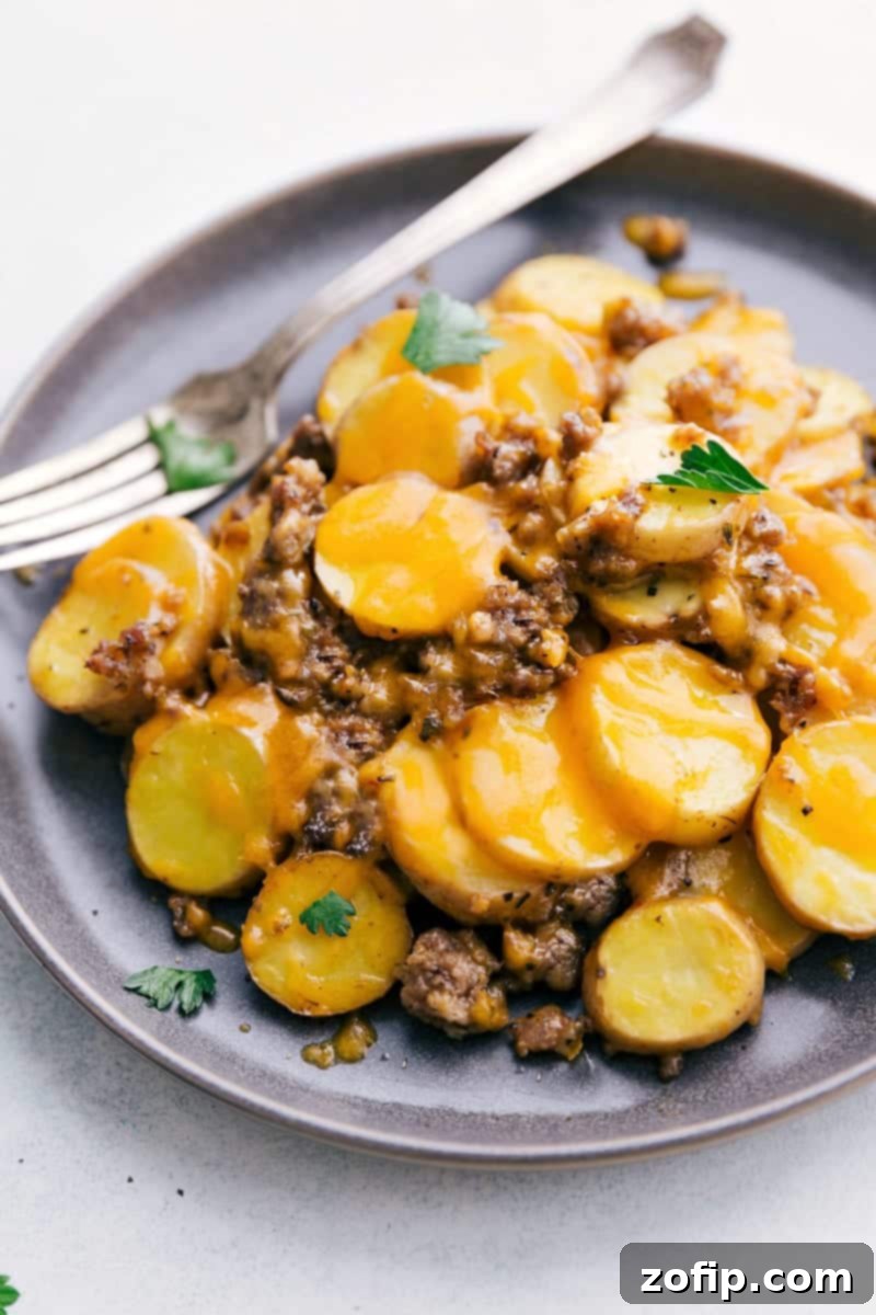 Simple and delicious comfort food: Crockpot Cheesy Potatoes! A large pot of Crockpot Cheesy Potatoes, topped with melted cheese and fresh parsley.