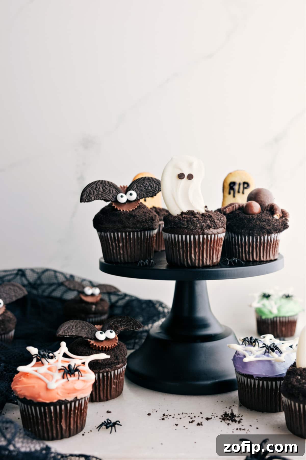 Fun And Festive Halloween Cupcakes Recipe Halloween cupcakes displayed on a cupcake holder feature a ghost, spider, bat, and tombstone cupcakes.
