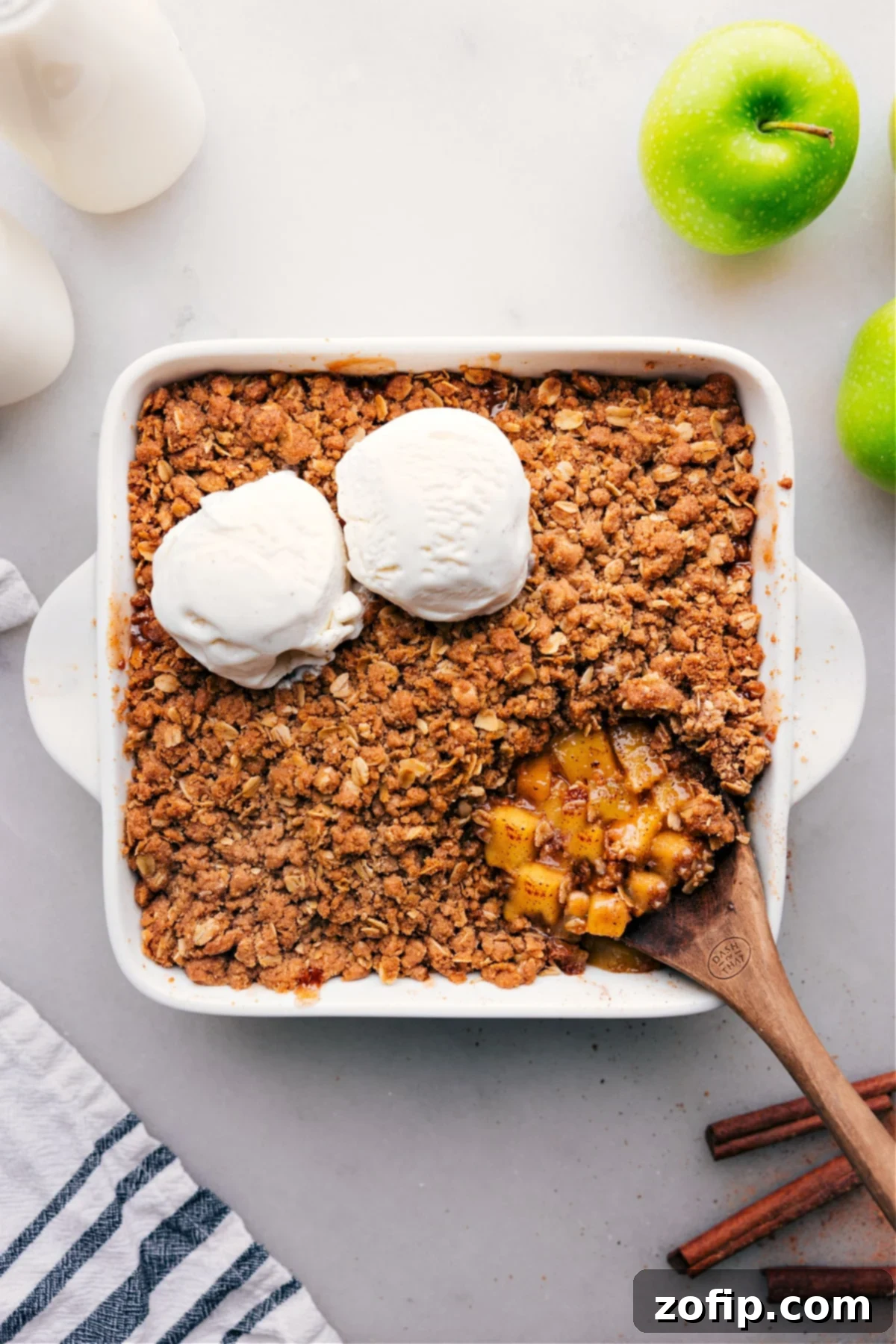 Golden-brown apple crumble in a dish topped with a scoop of melting vanilla ice cream, creating a mouth-watering contrast of warm and cold.