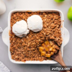 Overhead view of a golden-brown apple crumble in a square baking dish, ready to be served.