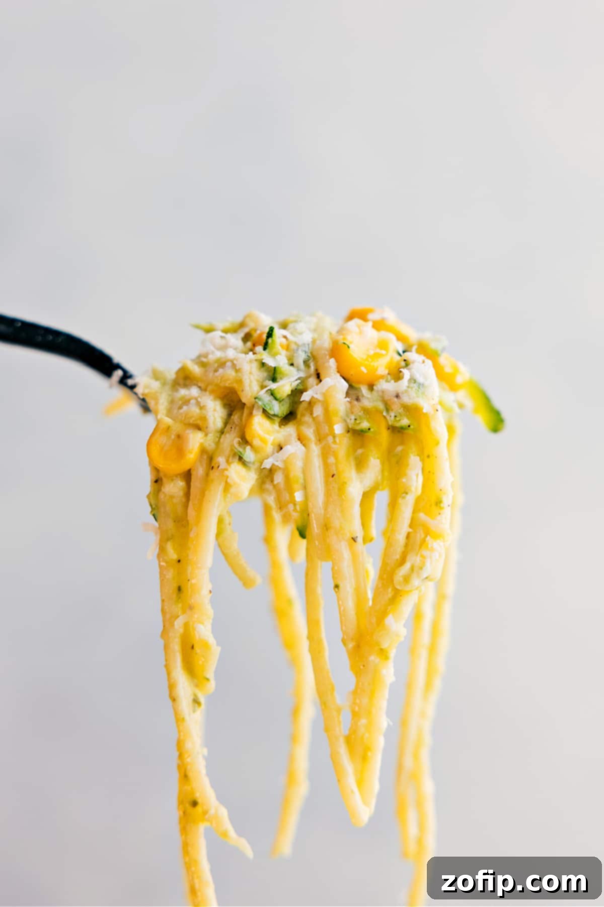A forkful of creamy Zucchini Squash Pasta, showing off the perfectly cooked spaghetti, tender zucchini, and vibrant pesto sauce, promising an irresistible bite.