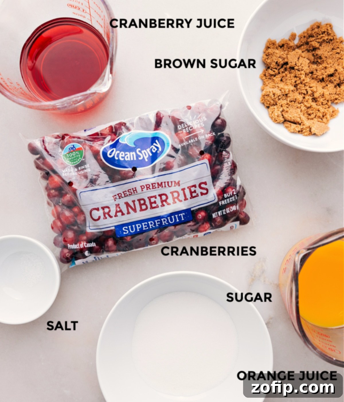 A selection of fresh cranberries, sugar, brown sugar, orange juice, cranberry juice, and a pinch of salt, all prepped for making homemade cranberry sauce.