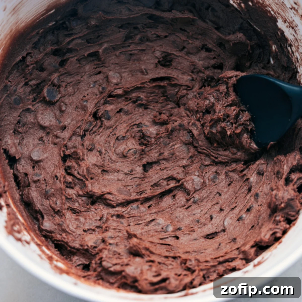 Thick, chocolatey brownie cookie dough mixed together in a bowl, ready to be scooped and rolled into perfect cookie balls.