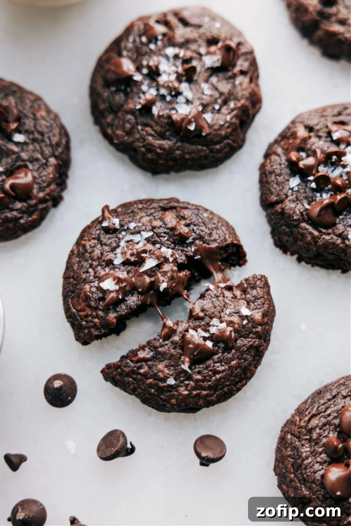 Freshly baked brownie cookies on a rustic board, with one cookie broken open revealing its rich, melted chocolate center.