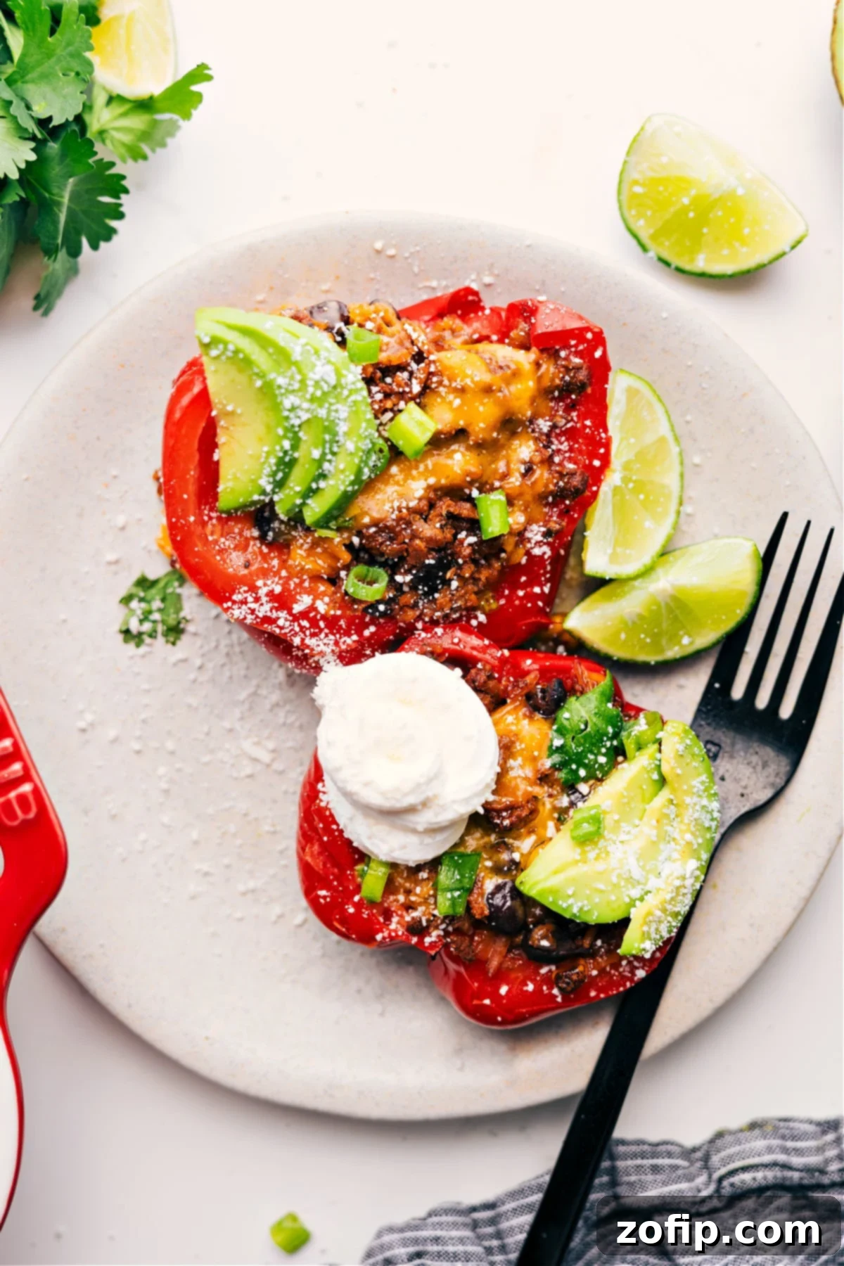 Enjoying Mexican Stuffed Peppers with All the Delicious Toppings A Mexican stuffed pepper cut in half, showcasing its rich filling, and topped with a generous dollop of sour cream, fresh avocado slices, vibrant cilantro, and spicy jalapeños, ready to be enjoyed.