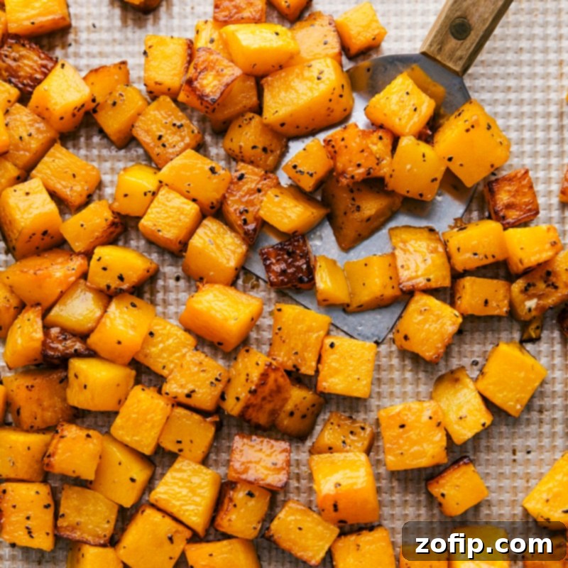 Roasted butternut squash, golden and tender, freshly removed from the oven and spread on a baking sheet.